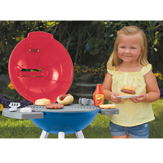 Girl with a toy barbecue grill set outdoors