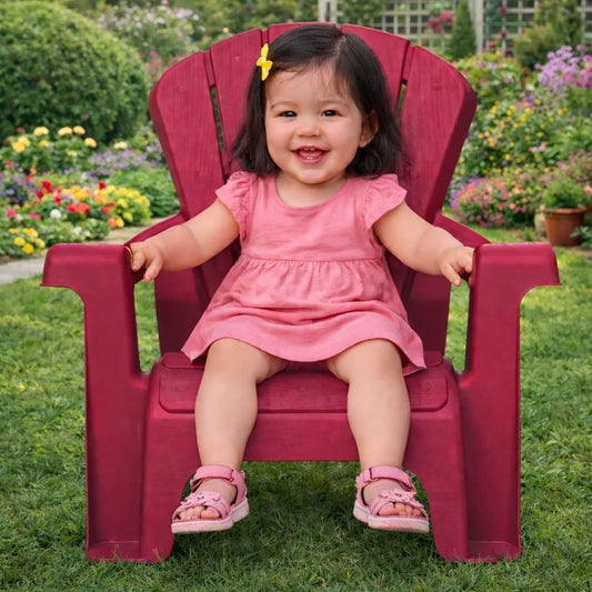 Child sitting on red chair with an outdoor background