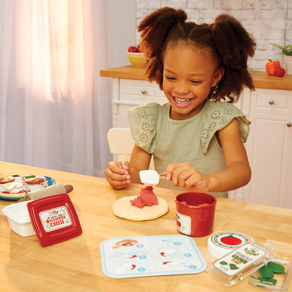 Girl adding pizza sauce to dough