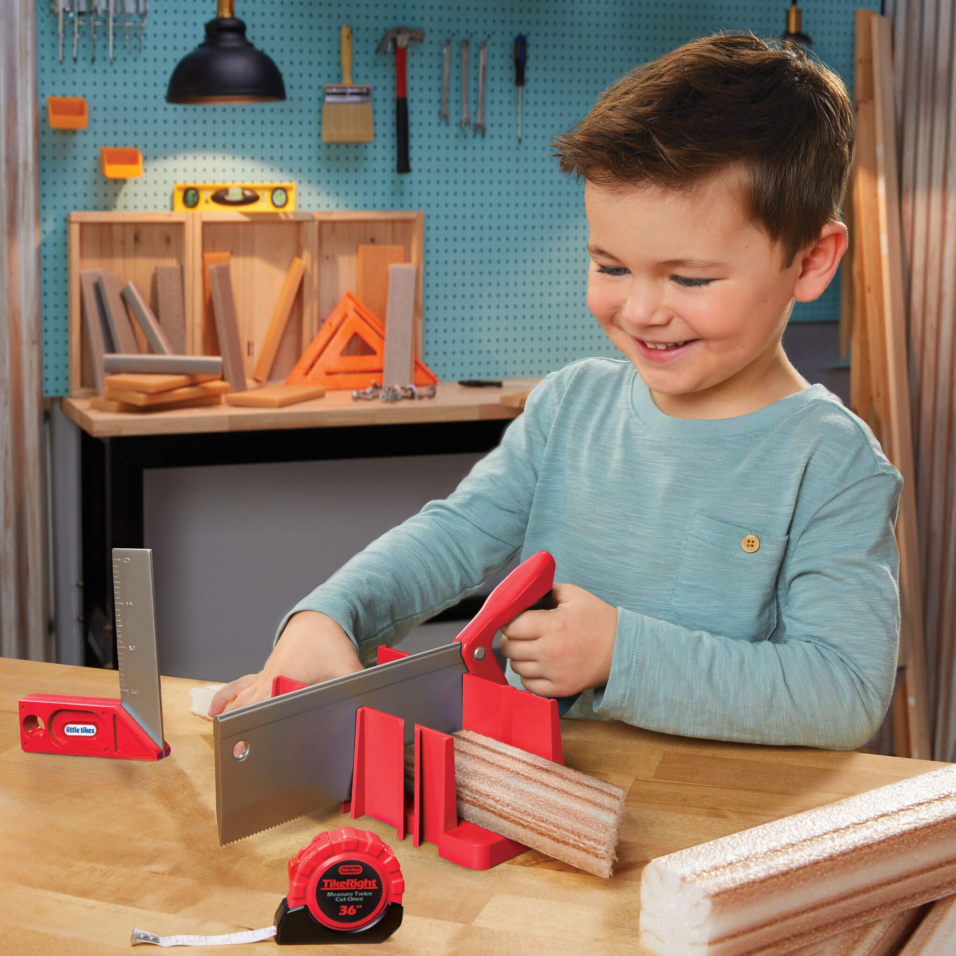 Boy playing with toy saw in a pretend workshop setting.