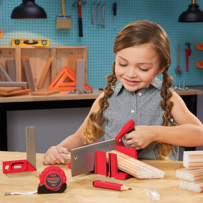 Girl using toy saw and other tools in a workshop setting