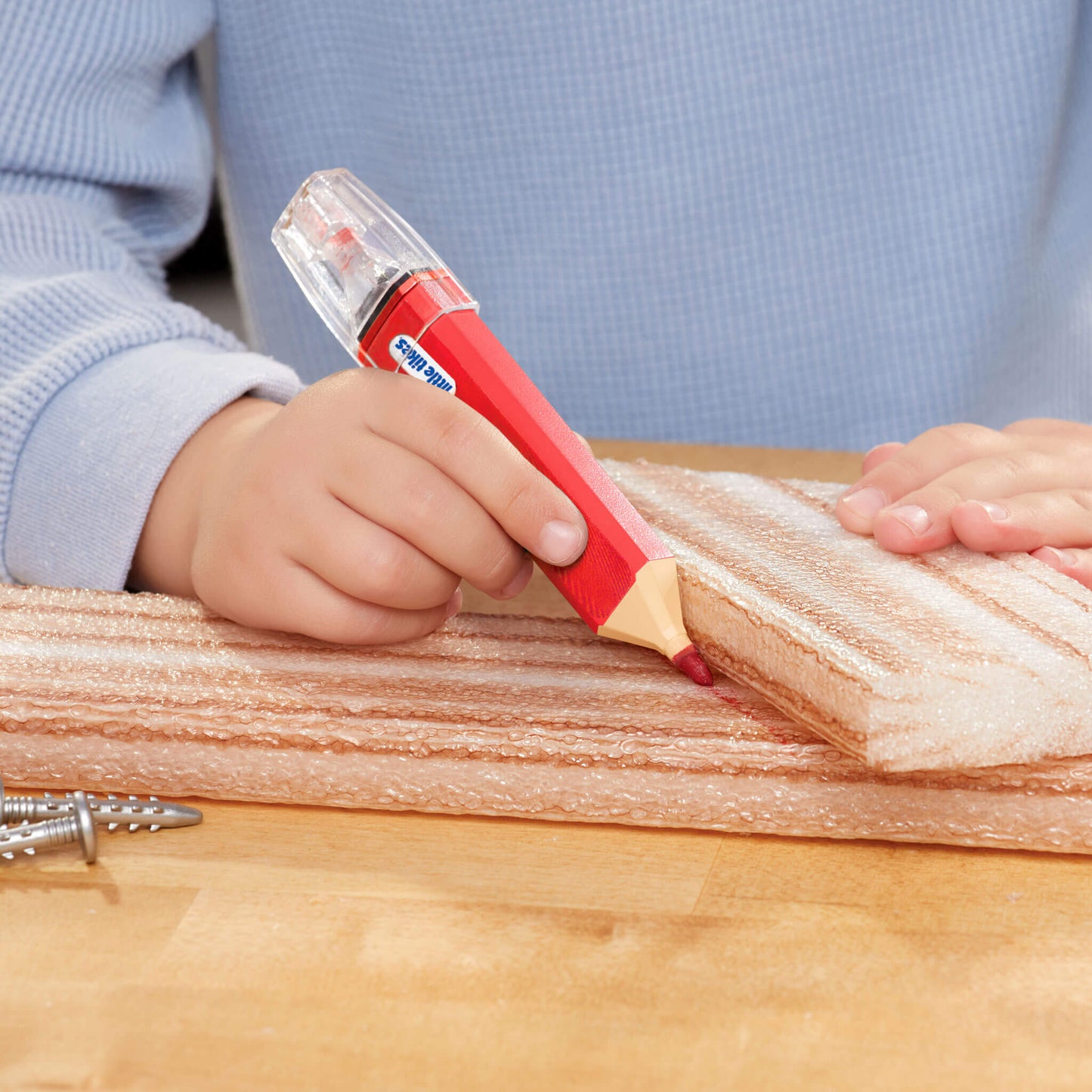 Child using a red pencil to make cut