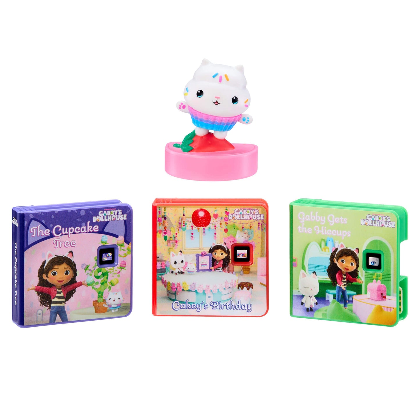 A set of Gabby's Dollhouse toy books and a small white cat figurine on a pink base, shown on a plain white background.