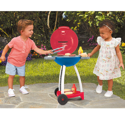 Two children playing with a toy barbecue set outdoors.