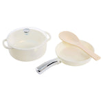 Set of white toy cookware with a lid, a pot, a pan, and a ladle on a white background