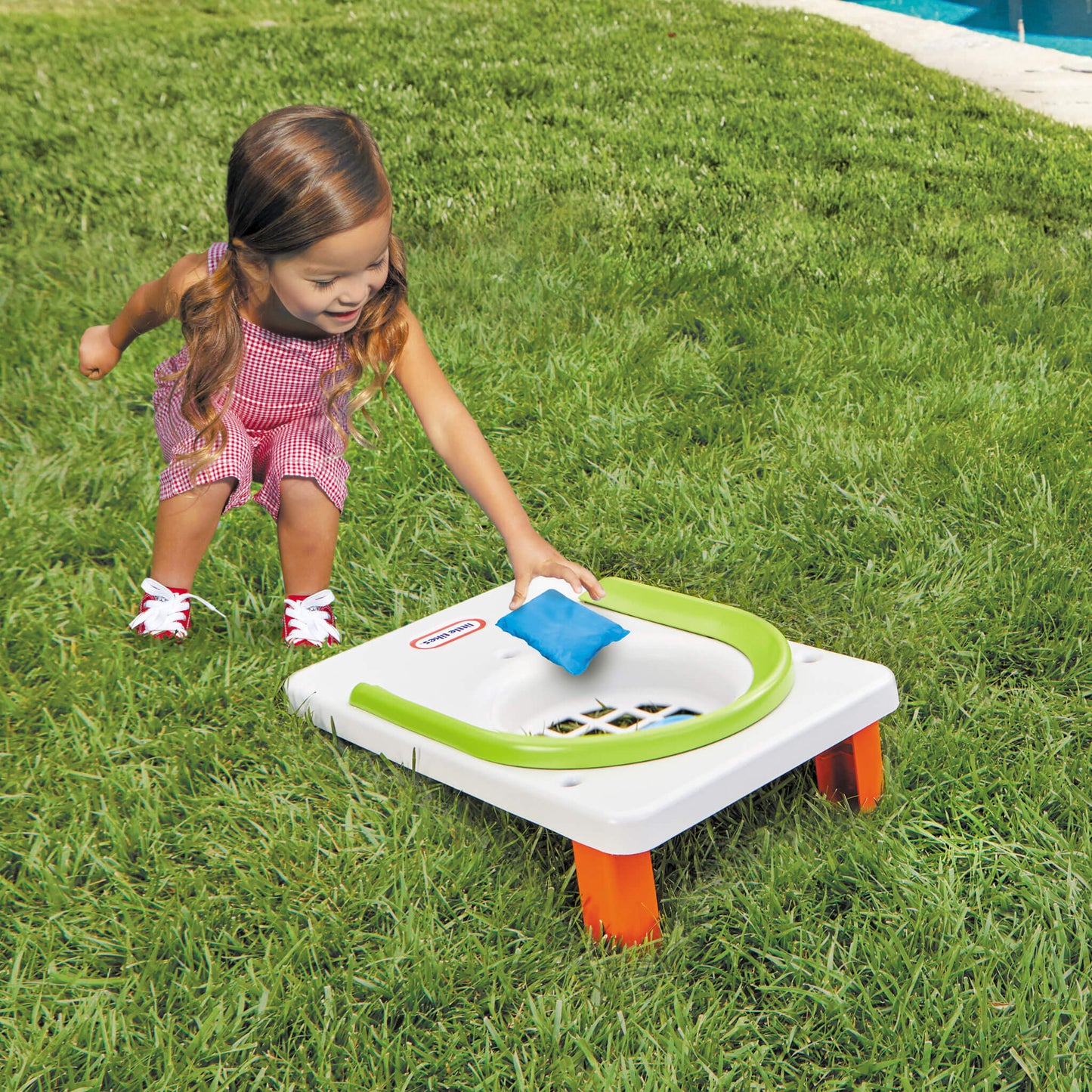 girl putting bean bag into cornhole