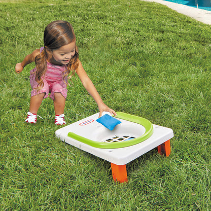girl putting bean bag into cornhole