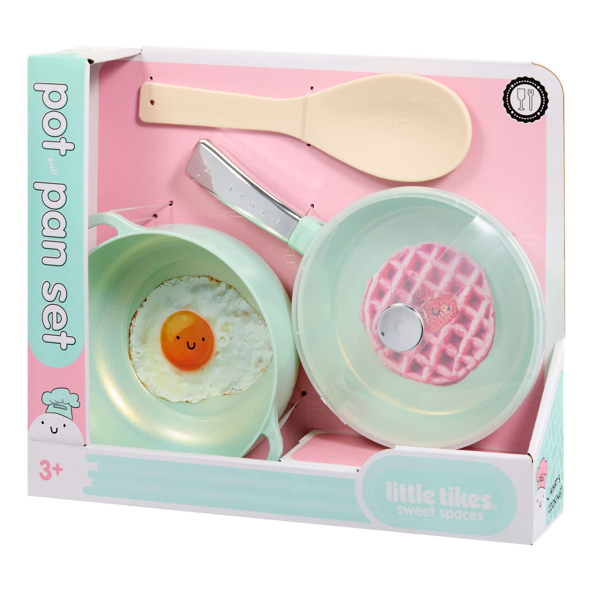 A children's pretend play cookware set in its retail box, featuring two pastel-colored frying pans with novelty food prints (a sunny-side-up egg and a waffle), a spoon, and a clear lid, branded 'Little Tikes Sweet Spaces'.