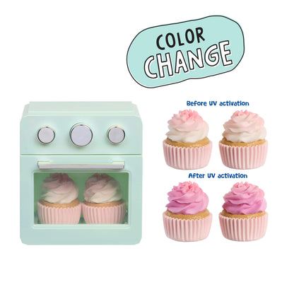 A toy miniature oven toy with two pink-and-white frosted cupcakes inside, shown on a white background with a 'COLOR CHANGE' graphic and before/after cupcake examples demonstrating a reversible color-changing feature.