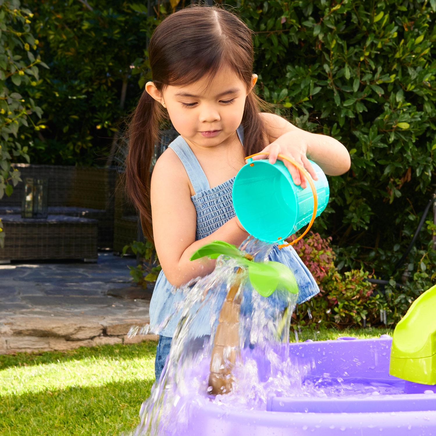 Girl pouring water on palm tree tops to make them twirl